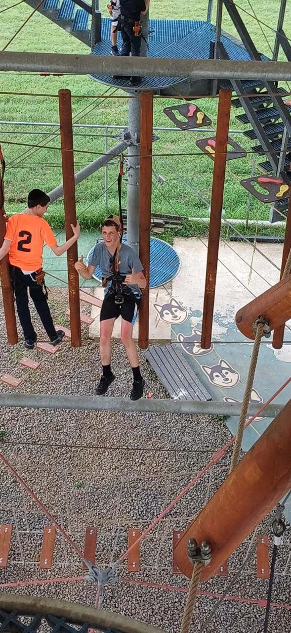 A camper wearing a harness on a ropes course